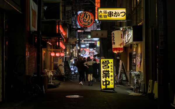 A lantern-lit Osaka back-street alley with small food shops at night